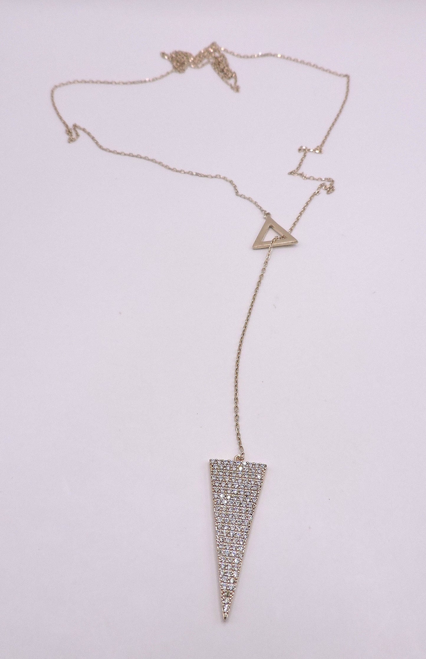 Rose gold silver necklace in the shape of an arrowhead, passed through a triangle.